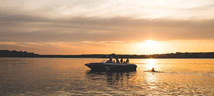 a tige boat in the water with a sunset view