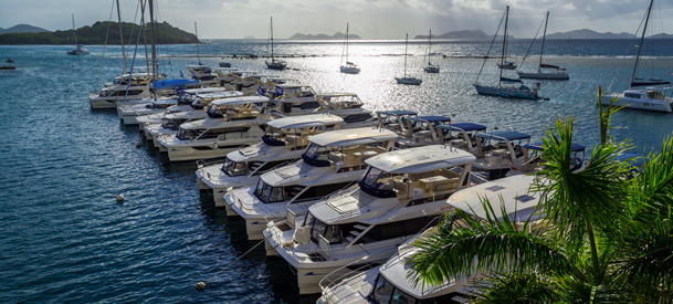 group of boats passing by dock filled with luxurious yachts