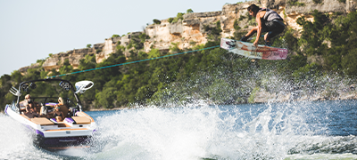 A wakeboarder catching some air behind a Tige RZX3