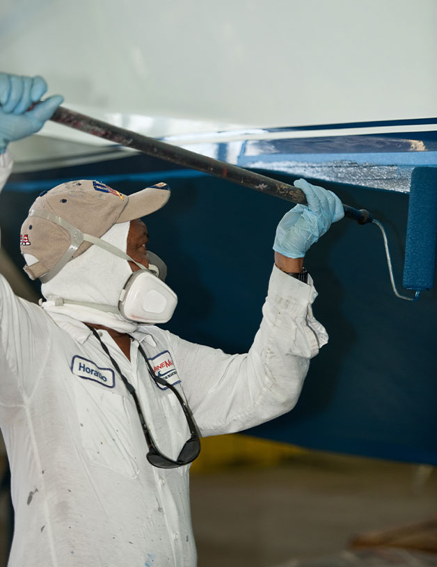 Service team member painting a boat
