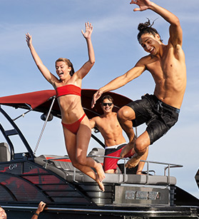 Kids jumping off of a Bennington pontoon boat into the water