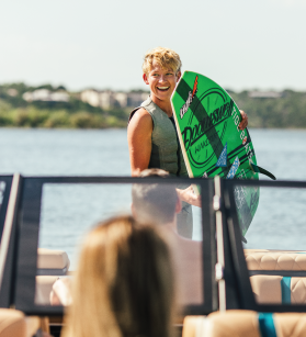 A boy with a wakeboard on a Tige boat