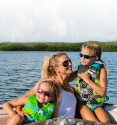 Mom and kids on a boat wearing life jackets for boat safety