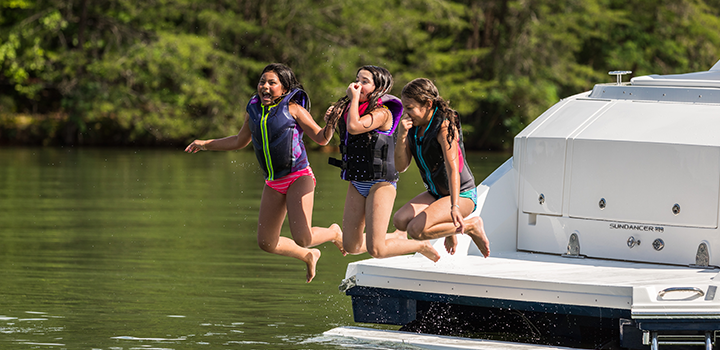 kids jumping off the back of a boat