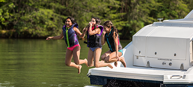 Kids jumping off the back of a boat