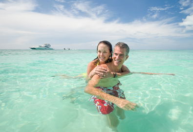 Couple in water with yacht behind them