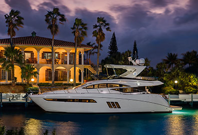 Sea Ray L590 in front of lit up house at night with lights reflecting on water