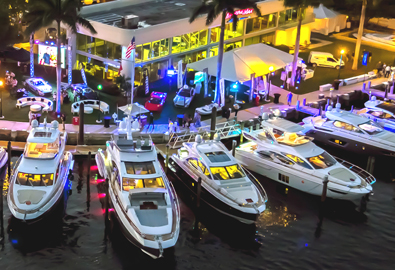 People walking on colorful pier lined with yachts and supercars at marinemax boat show
