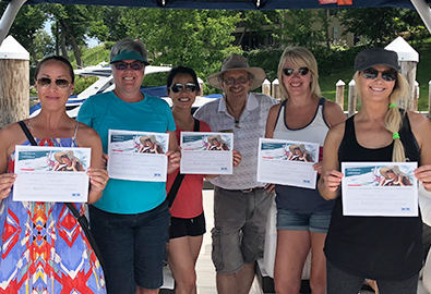 group of women standing on a boat holding certificates