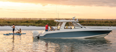 Boston Whaler boat out on the water at dusk with a paddleboarder 