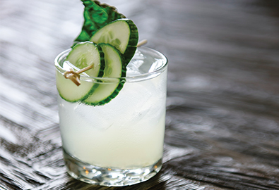 green gimlet cocktail in glass with cucumbers