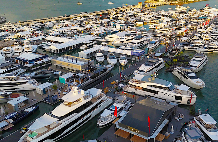 overhead view of a bustling marina with numerous white yachts and boats docked closely together white tents and piers are visible set against a calm greenish sea