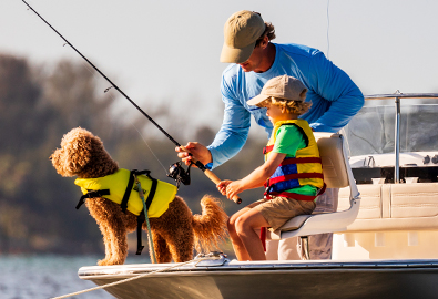A man, boy, and dog fishing on a boat