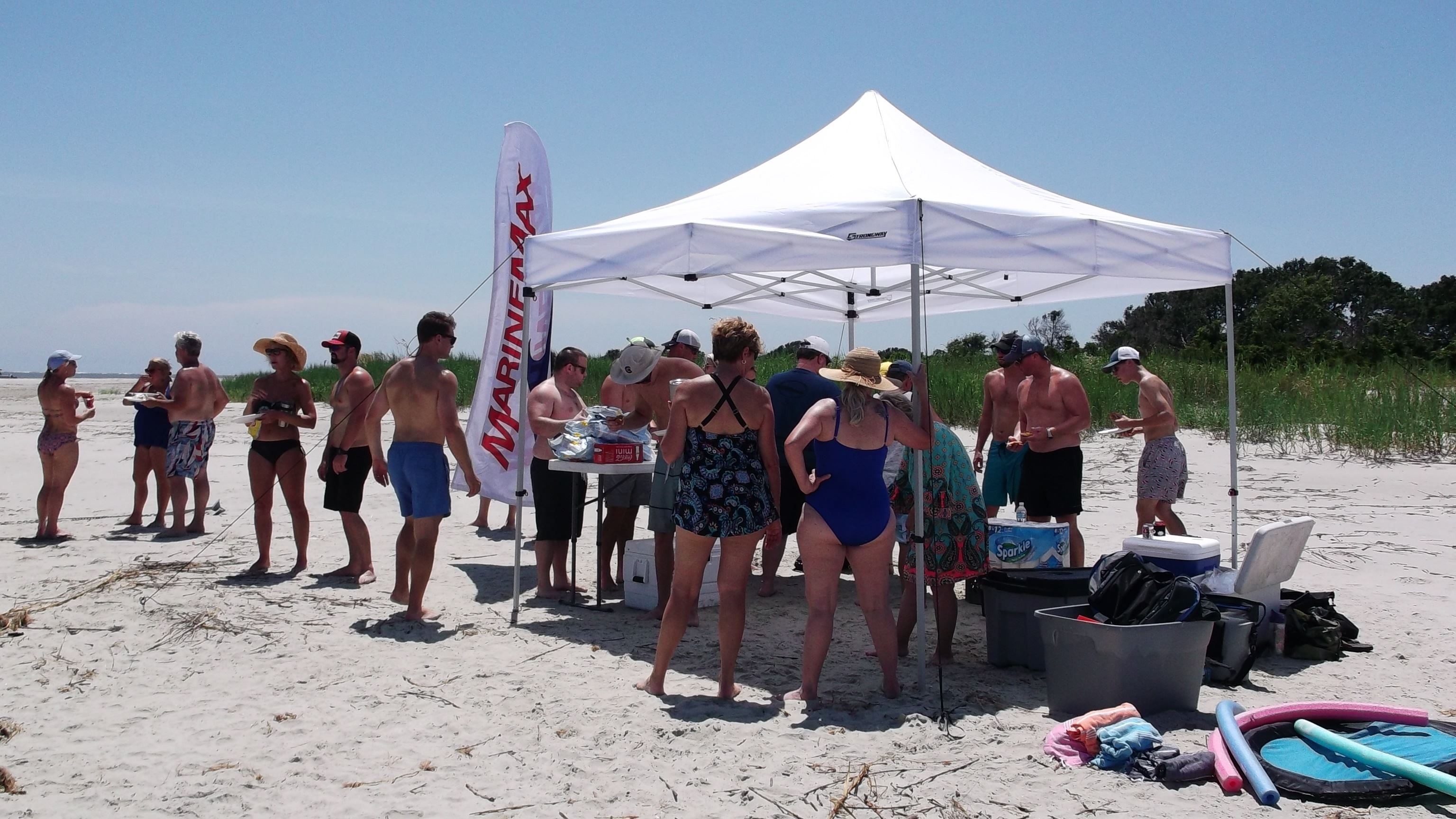 people getting food from tent and eating on beach at kiawah cookout