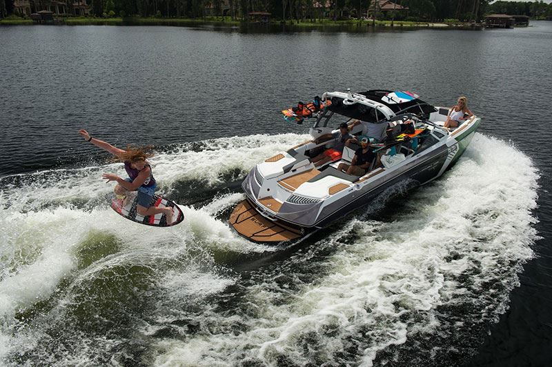 Wake boarding jumping midair while being pulled by a ski boat with friends