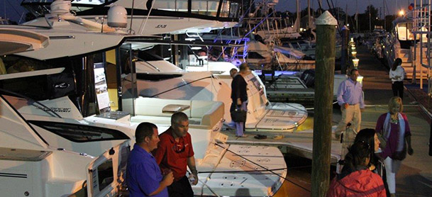 boats tied to dock at night with people walking along the dock