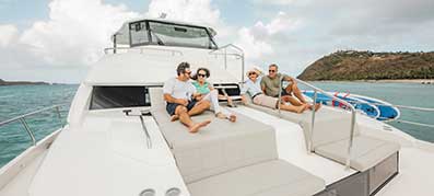 Two couples relaxing on the bow seating of a yacht
