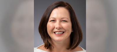 Amanda Ward smiling with shoulder-length brown hair against a gray background. She's wearing a light-colored top, conveying a friendly, approachable tone.
