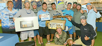A group of twelve men celebrate winning a fishing tournament, holding trophies and prize boxes.