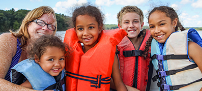 4 kids wearing a life jacket and adult on the boat