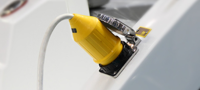 A photo of a yellow power plug inserted into a boat for shore power