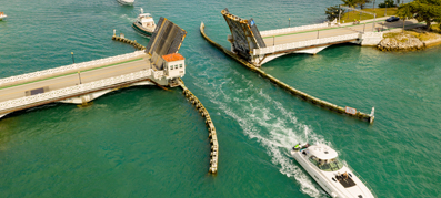 A picture of a yacht going through an open bridge