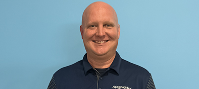 Thomas Ortmann smiling against a light blue background, wearing a navy polo shirt with "MarineMax" branding and a name tag.