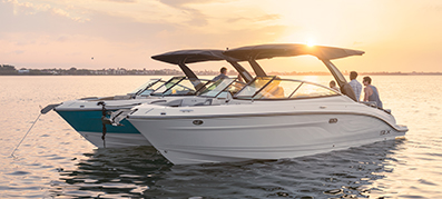 Two white boats float on calm water at sunset, casting gentle reflections.