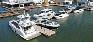 A marina with several white yachts docked on calm water.