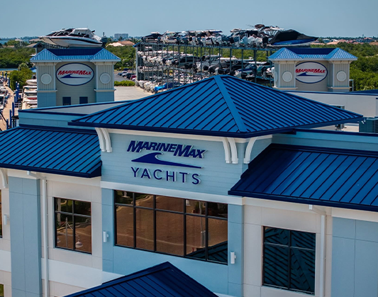 A marina with boats docked near MarineMax Fort Myers building featuring a blue roof.