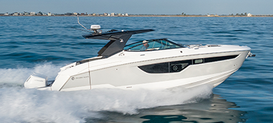 A sleek white motorboat speeds across a calm blue sea, creating a dynamic wake.