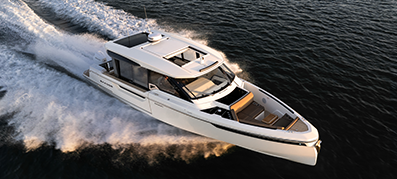 A sleek white luxury pilothouse boat swiftly cruises through dark blue water, leaving white wake trails.