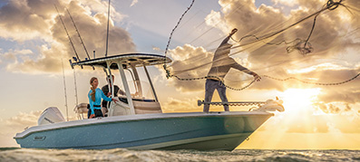 Man throwing fishing net off boat with others standing on boat