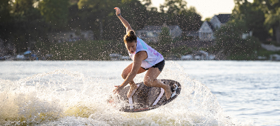 Surfer in mid-air performing a trick on a wave, with water droplets sparkling around.
