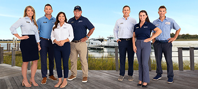 seven MarineMax team members posing and smiling with  water backdrop
