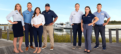 seven MarineMax team members posing and smiling with water backdrop