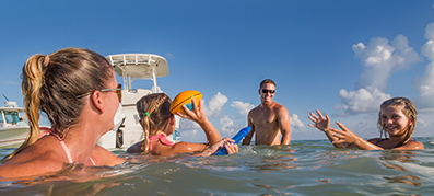 family and friends playing in the water next to their boat