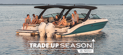 A family on an outboard boat with with the MarineMax Trade Up Season logo
