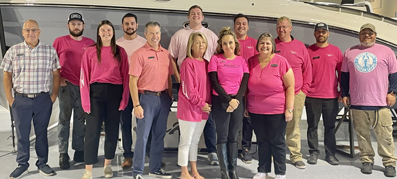 A group of 14 MarineMax team members wearing pink shirts in support of breast cancer awareness.