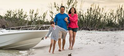 Family hanging out on a beach infront of a boston whaler