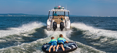 young boaters tubing behind an outboard boat