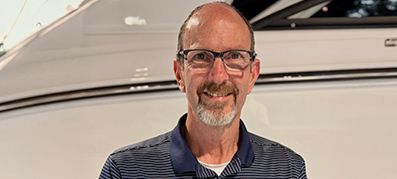 The new GM of MarineMax Danvers, Ron Baker, smiles warmly in front of a white yacht.