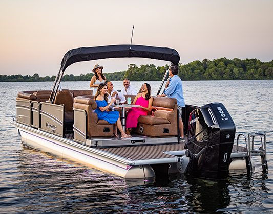 group of people on a pontoon boat with sunset in the background