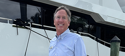 Cary Smart, Director of Motor Yachts, poses next to a boat at the dock, showcasing his passion for boating.