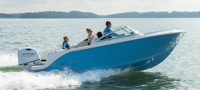 A blue motorboat with four people, including a child in a life jacket, speeds across a calm lake.