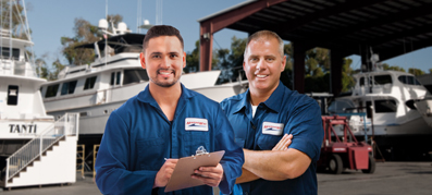 two service team members smiling in front of boats