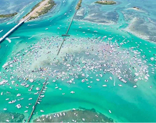 Aerial view of boats on water during the H2O Music Festival, showcasing vibrant colors and lively atmosphere.