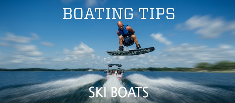 A man does a trick in the air in the wake of a white ski boat