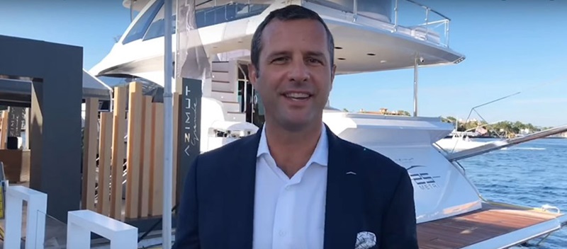man standing in front of yacht smiling