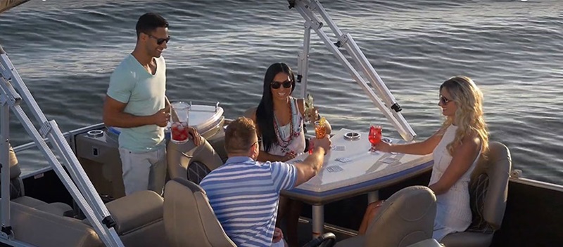 group of people drinking around a table on a bennington pontoon